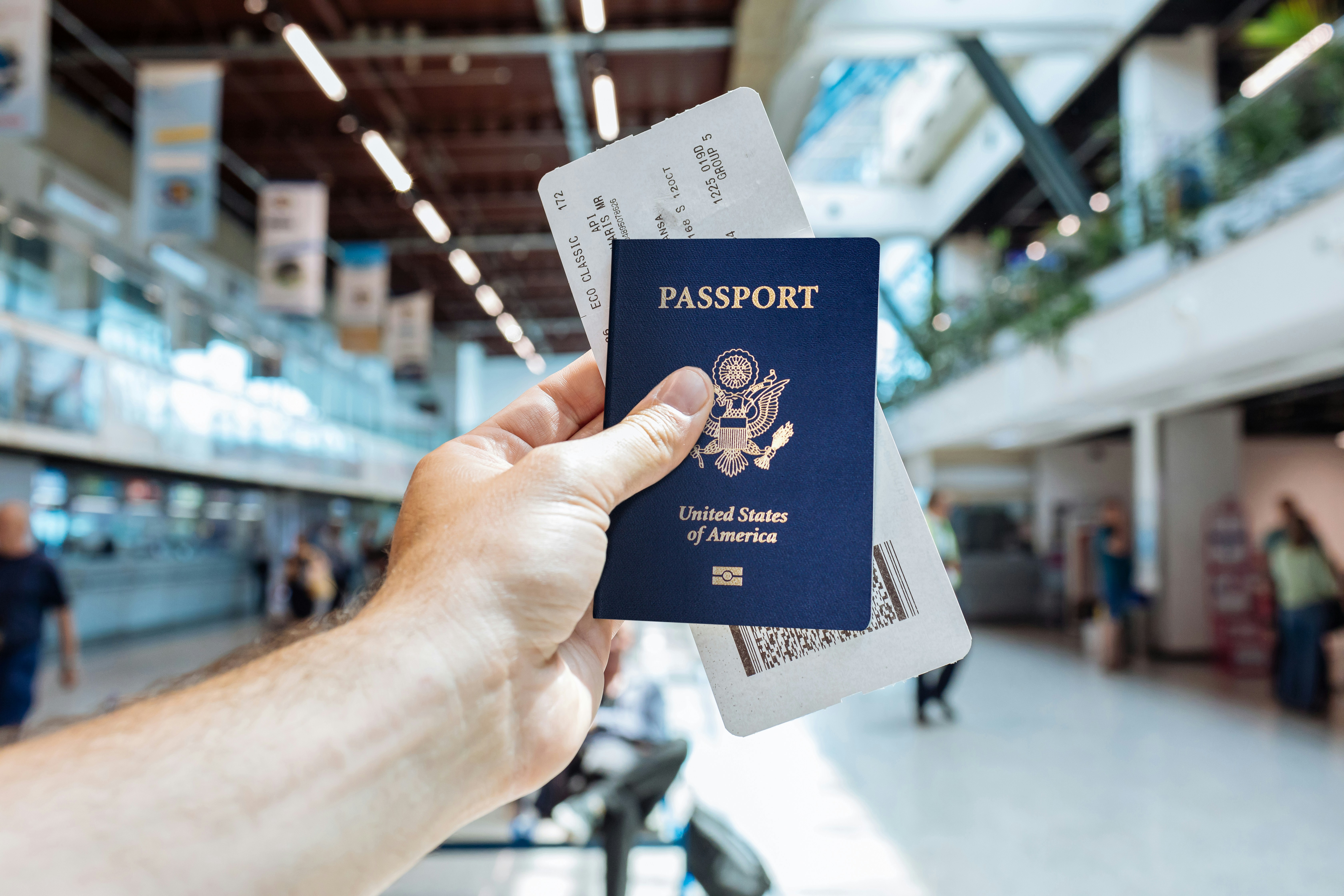 A traveler walking through a major US airport hub holding a passport during their first time visiting the USA